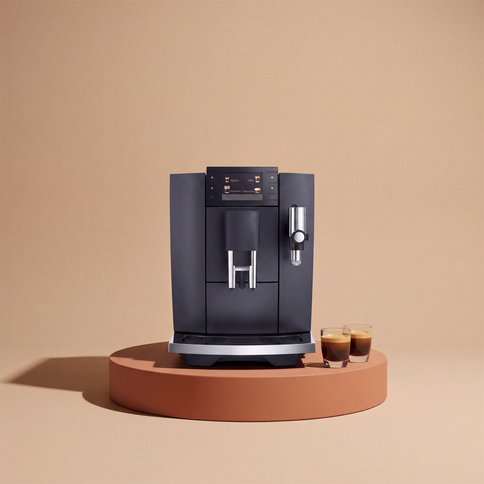 Cafetera superautomática sobre fondo beige con dos espressos
